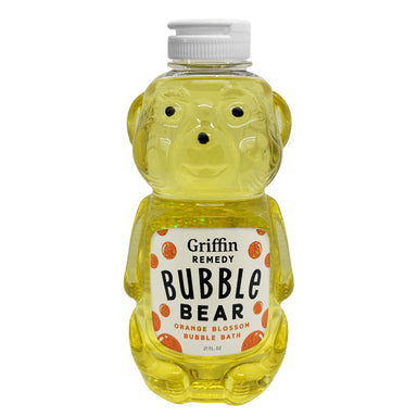 A plastic bottle in the shape of a teddy bear with a yellow bubble bath inside, labeled 'Griffin Remedy Bubble Bear Orange Blossom Bubble Bath'. Natural skincare.