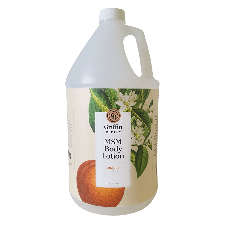 A gallon bottle of Griffin Remedy MSM Body Lotion with Orange Blossom scent, featuring a label with orange flowers and product information. Natural skincare.