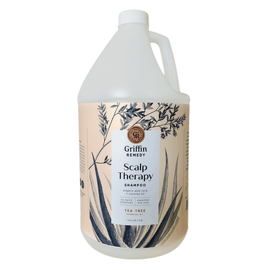 A gallon-sized bottle of Griffin Remedy Scalp Therapy Shampoo with a label featuring botanical illustrations and text that reads 'TEA TREE'. Natural hair care.