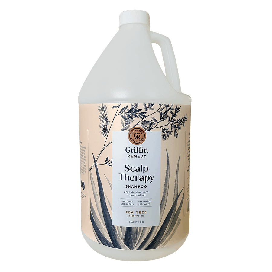 A gallon-sized bottle of Griffin Remedy Scalp Therapy Shampoo with a label featuring botanical illustrations and text that reads 'TEA TREE'. Natural hair care.