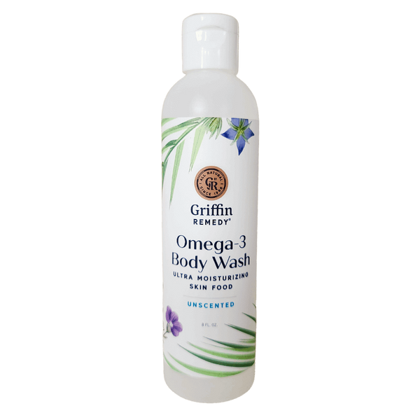 A bottle of Griffin Remedy Omega-3 Creamy Body Wash with a label that includes the product name and 'Unscented' beside it. The bottle is white with green and blue floral design accents. Natural skincare.